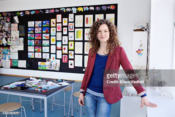 portrait of teacher standing in classroom - lehrtätigkeit stock-fotos und bilder