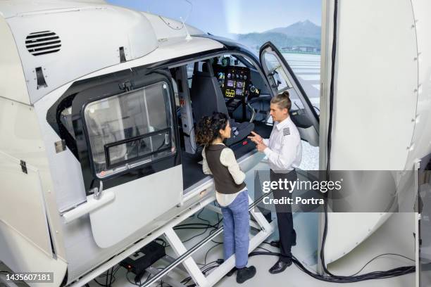 istruttore pilota che fornisce indicazioni al pilota tirocinante durante la sessione di addestramento nel simulatore di elicottero - simulatore foto e immagini stock