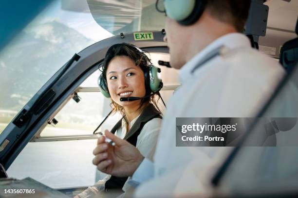 woman learning to fly helicopter with instructor inside a flight simulator - flying school stock pictures, royalty-free photos & images