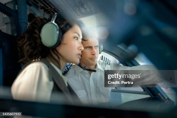 male pilot talking with woman trainee pilot sitting inside a flight simulator - vlieger stockfoto's en -beelden