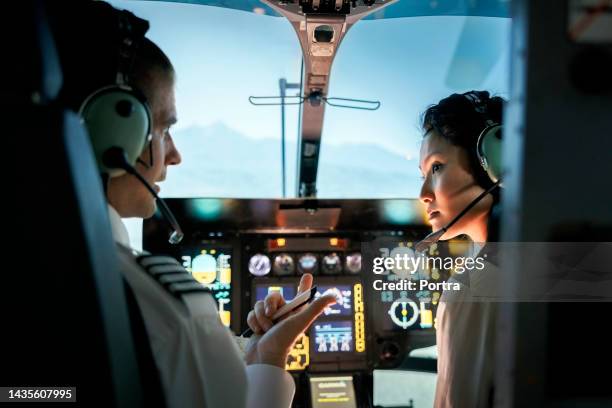 female trainee pilot listening to instructor during a flight simulation training - 領航員 個照片及圖��片檔