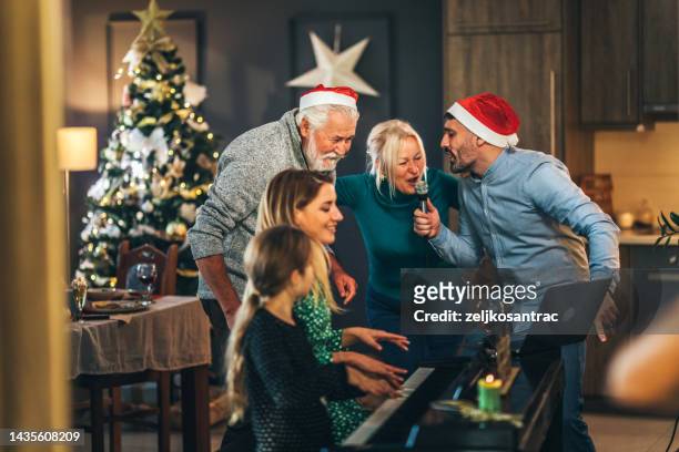mehrgenerationenfamilie singt weihnachtslied auf hausparty - karaoke anlage stock-fotos und bilder