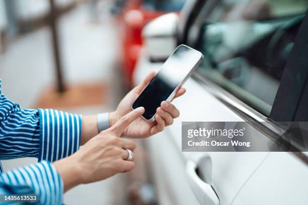 female hand unlocking car with smart phone. - comprar coche fotografías e imágenes de stock