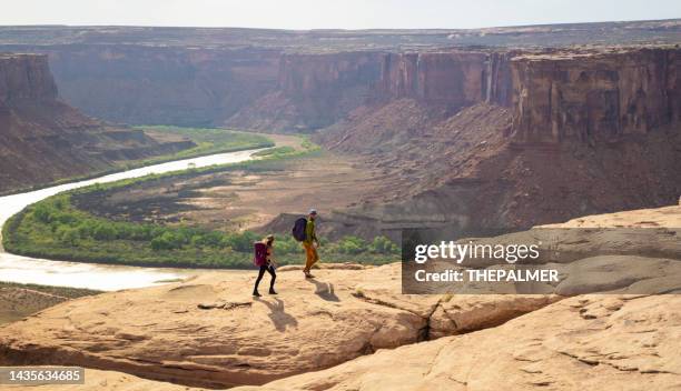 pareja joven caminando en moab park, ee.uu. - moab utah fotografías e imágenes de stock