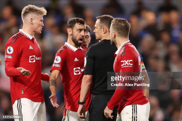 Match referee Stuart Attwell is confronted by Bruno Fernandes and teammates after awarding a penalty to Chelsea during the Premier League match...