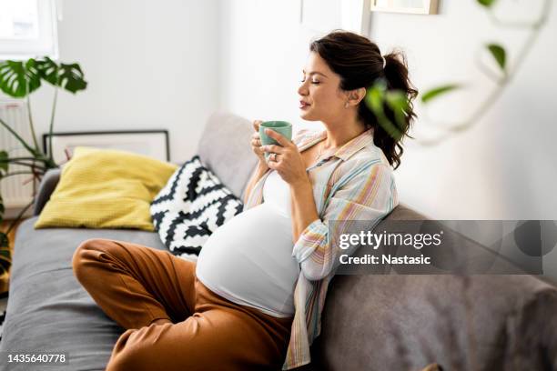 pregnant woman resting on sofa drinking coffee - family on couch with mugs stock pictures, royalty-free photos & images