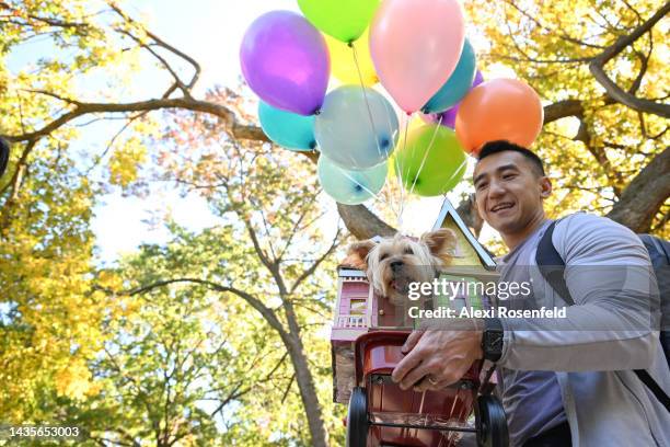 Billy Chan holds his dog, Allie the terroir, dressed as UP during the Annual Tompkins Square Halloween Dog Parade on October 22, 2022 in New York...