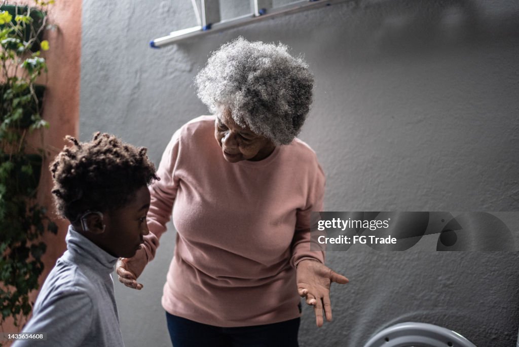 Abuela dando un regaño a su nieto en la lavandería de casa