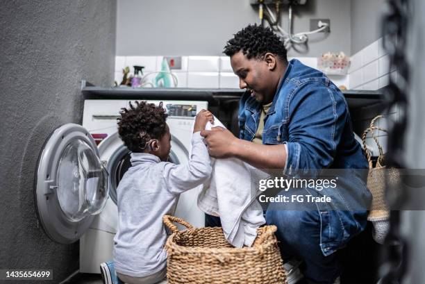 father and son washing clothes in the laundry at home - man washing basket child stock pictures, royalty-free photos & images