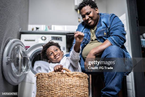 father and son flying on a basket in the laundry at home - man washing basket child stock pictures, royalty-free photos & images