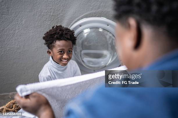 father and son washing clothes in the laundry at home - man washing basket child stock pictures, royalty-free photos & images