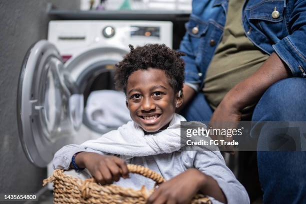 portrait of little boy playing on a basket in the laundry at home - man washing basket child stock pictures, royalty-free photos & images