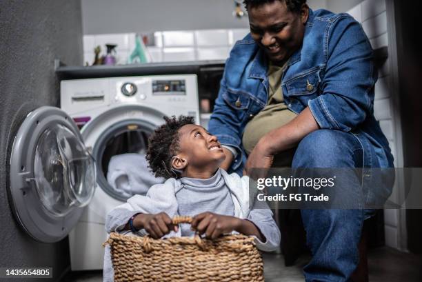 father and son playing on a basket in the laundry at home - man washing basket child stock pictures, royalty-free photos & images