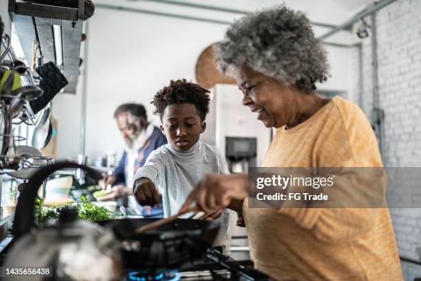 nipote che aiuta la nonna a cucinare a casa - african american grandparents foto e immagini stock