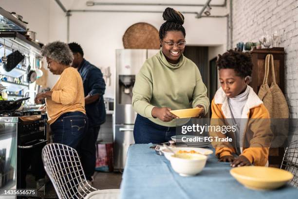 familie deckt den tisch und bereitet das mittagessen zu hause vor - familie zuhause essen stock-fotos und bilder