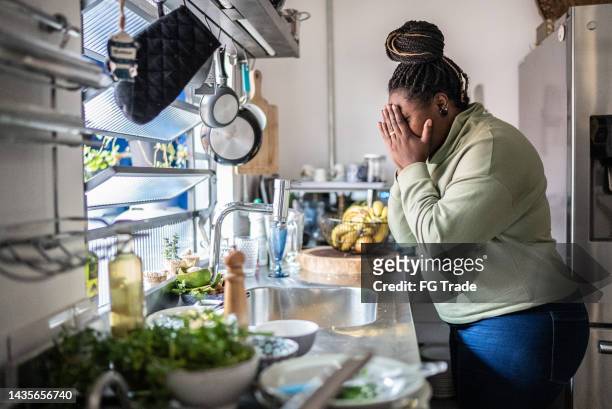 triste mujer mediana adulta en la cocina de casa - in case of discomfort fotografías e imágenes de stock
