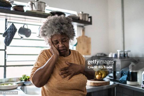 mujer mayor preocupada en la cocina de casa - in case of discomfort fotografías e imágenes de stock