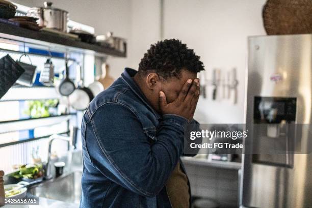 sad mid adult man in the kitchen at home - terrified stock pictures, royalty-free photos & images