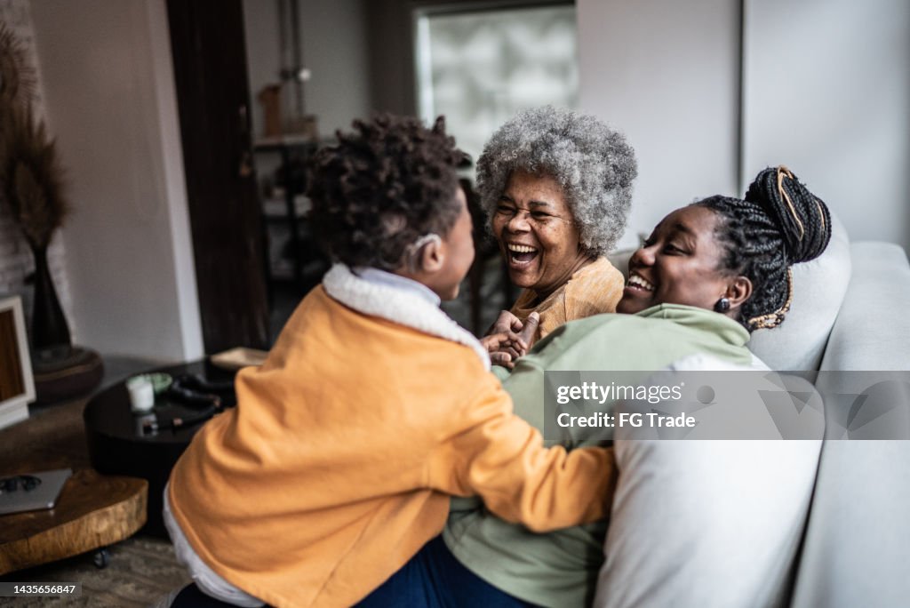 Child playing with his mother and grandmother in the living room at home