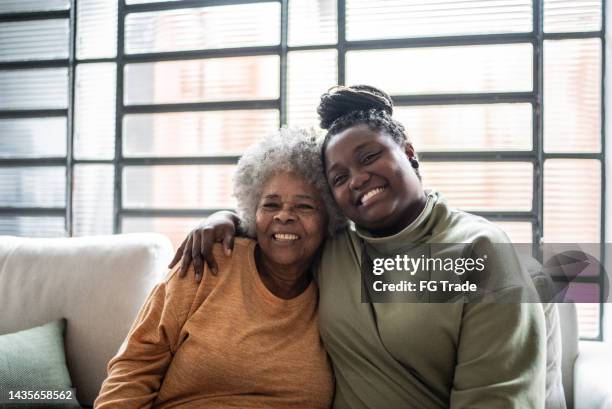 portrait of a mother and daughter embracing at home - black mother stock pictures, royalty-free photos & images