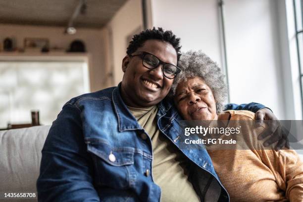 retrato de madre e hijo en la sala de estar de su casa - hijo adulto fotografías e imágenes de stock