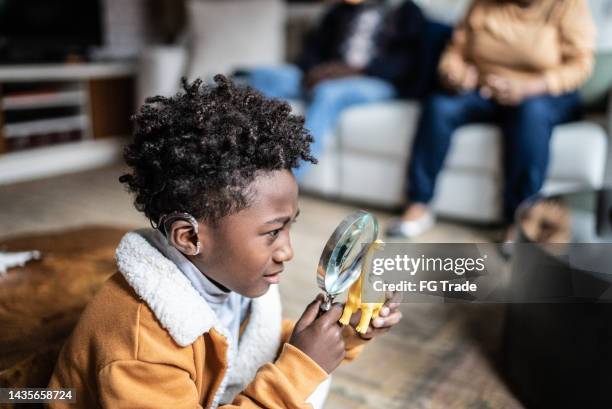 niño mirando un juguete con una lupa en casa - animal extinto fotografías e imágenes de stock