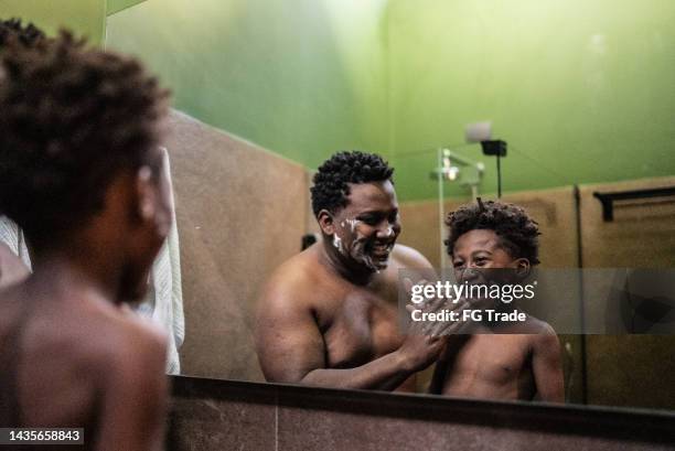 padre e hijo jugando con crema de afeitar en el baño de casa - crema de afeitar fotografías e imágenes de stock