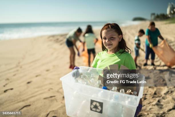 portrait of recycler girl with plastics in a bin at the beach - plastic pollution beach stock pictures, royalty-free photos & images