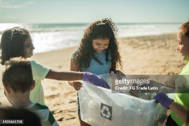 children collecting garbage at the beach - clean ocean stock pictures, royalty-free photos & images
