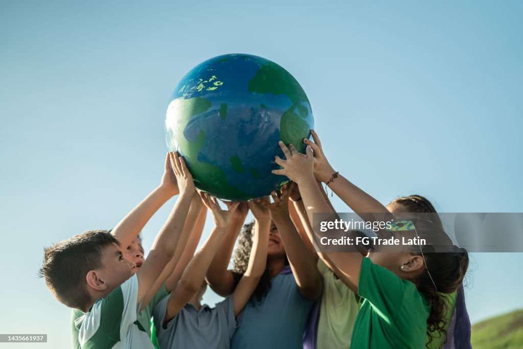 Niños sosteniendo un planeta al aire libre