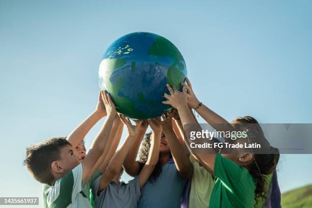 children holding a planet outdoors - eco age earth day event stockfoto's en -beelden