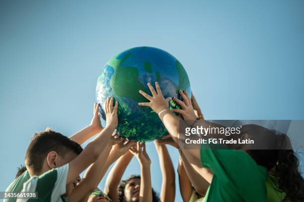 children holding a planet outdoors - eco age earth day event stockfoto's en -beelden