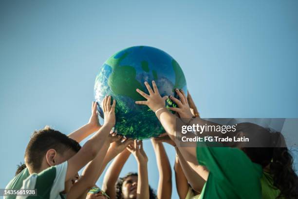 children holding a planet outdoors - climate change children stock pictures, royalty-free photos & images