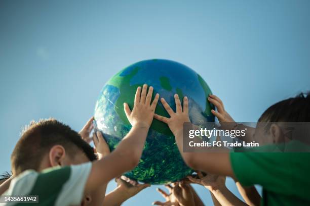 bambini che tengono un pianeta all'aperto - earthday foto e immagini stock