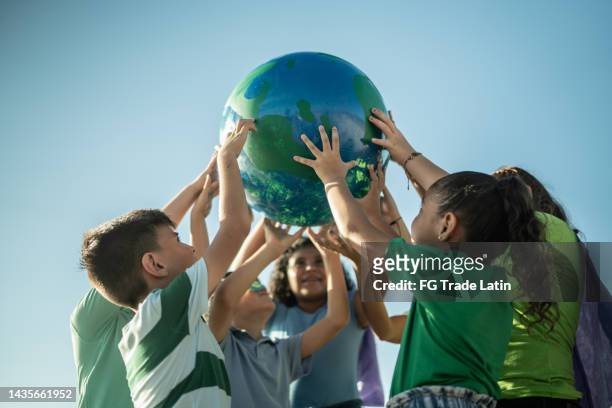 niños sosteniendo un planeta al aire libre - children charity fotografías e imágenes de stock