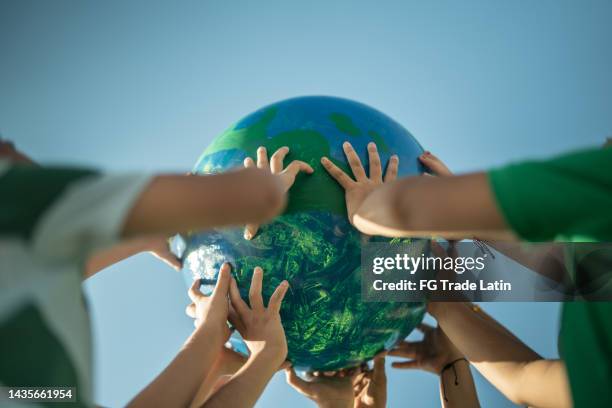 niños sosteniendo un planeta al aire libre - cambio climático fotografías e imágenes de stock