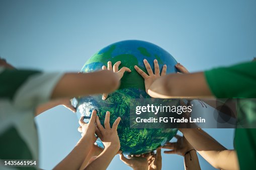 Crianças segurando um planeta ao ar livre Crianças segurando um planeta ao ar livre