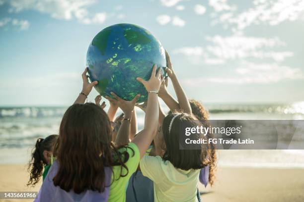 enfants tenant une planète à la plage - action climatique photos et images de collection