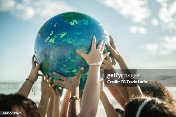 nahaufnahme von kindern, die einen planeten am strand halten - community events stock-fotos und bilder