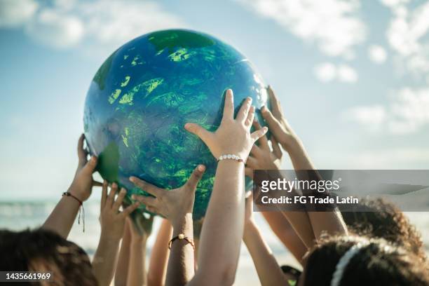 close-up of children holding a planet at the beach - sustainable resources stock pictures, royalty-free photos & images