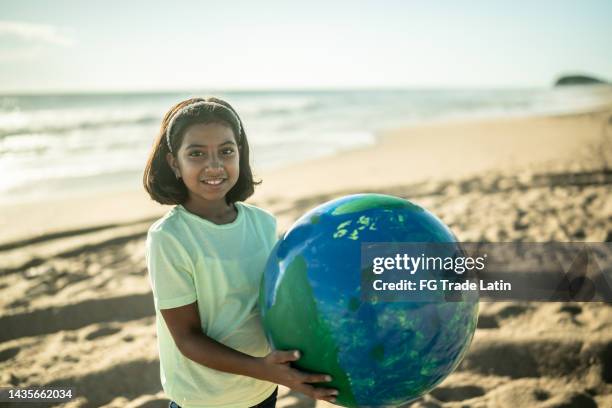 portrait of girl holding a planet sphere at the beach - world children day stock pictures, royalty-free photos & images