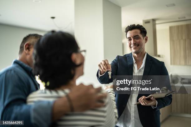 agente inmobiliario entregando las llaves de la casa a un cliente en casa - pasar fotografías e imágenes de stock