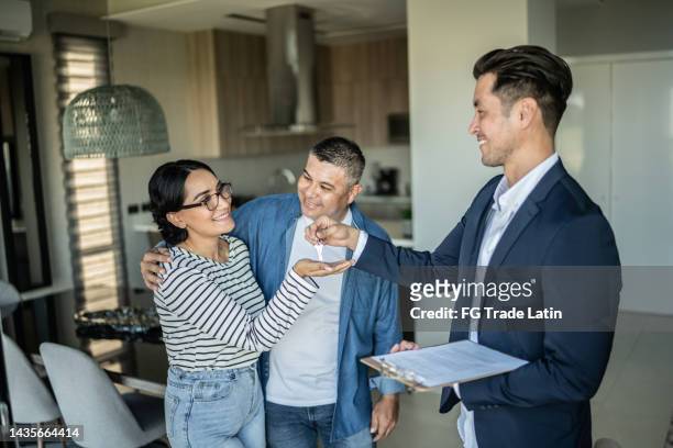 real estate agent giving  the home keys to a couple at home - pact for mexico stock pictures, royalty-free photos & images