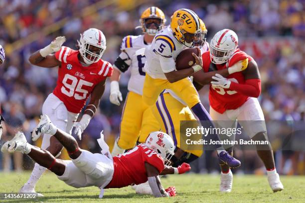 Jayden Daniels of the LSU Tigers hurdles over Markevious Brown of the Mississippi Rebels during the first half at Tiger Stadium on October 22, 2022...