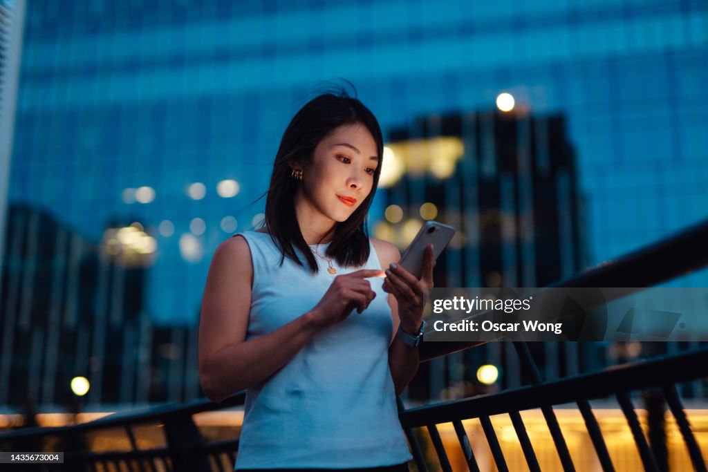 Young Asian woman using smartphone in the city at night