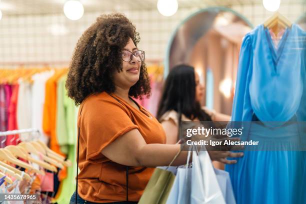 woman choosing clothes in boutique - plus size fashion stock pictures, royalty-free photos & images