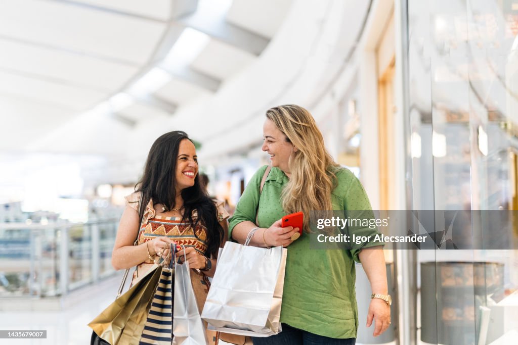 Smiling women carrying shopping bags in the mall