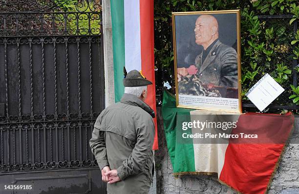 Man attends a commemoration ceremony for the death of Italian dictator Benito Mussolini and his mistress, Claretta Petacci in front of a headstone of...