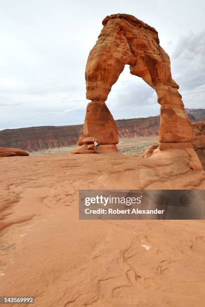 Visitor to Arches National Park near Moab, Utah, walks along the base of the park's best known attraction, Delicate Arch. The park contains the...