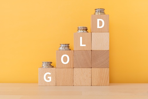 Wooden blocks with "GOLD" text of concept and coins.